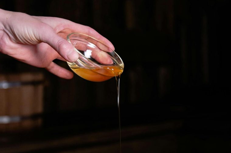 A hand pouring oil onto skin for a soothing massage in a spa setting.