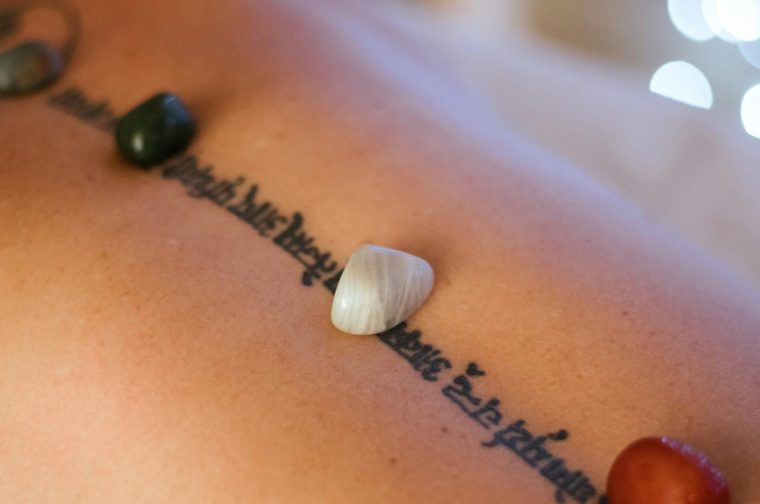 Spa therapy session featuring healing stones on a woman's back for relaxation and wellness.